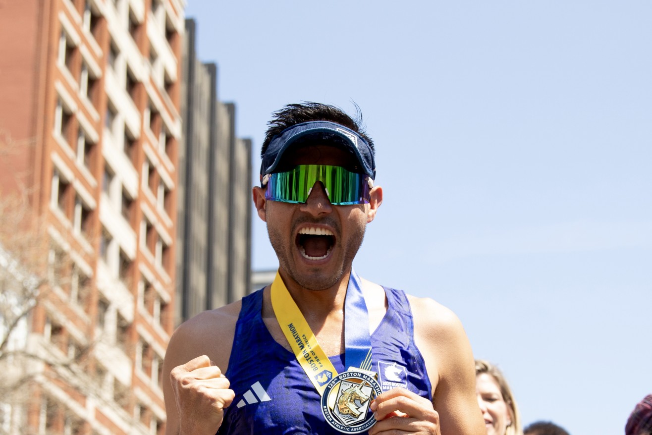Man in a blue tank top presents a medal